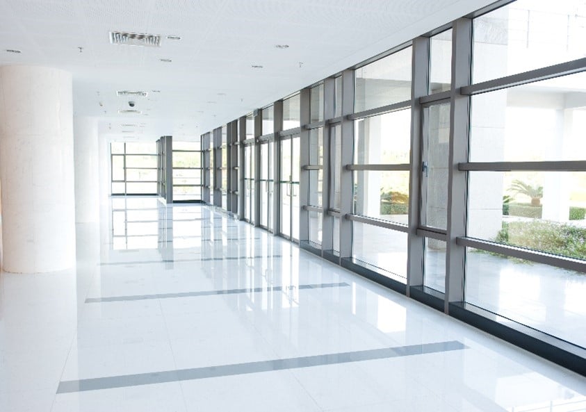 An image of a clean building with shiny white floors and large windows with black framing.