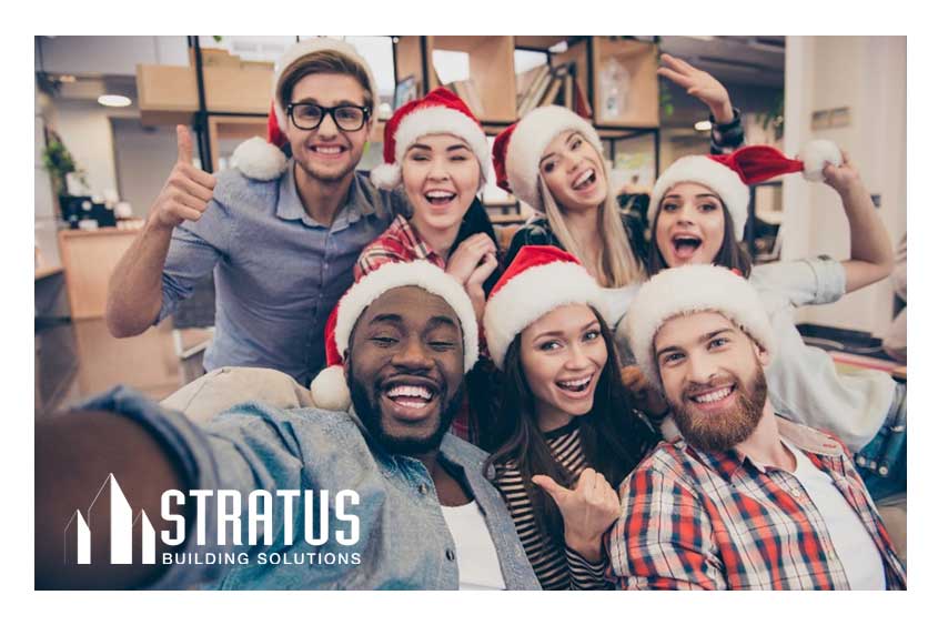 Seven coworkers taking a selfie while wearing Santa hats during their holiday office party.