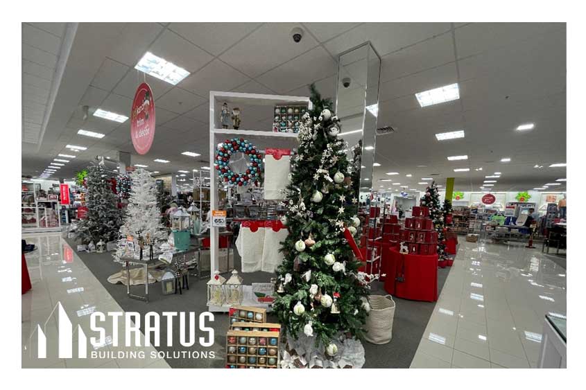 Interior of a retail store that is decorated for Christmas with several Christmas trees and ornaments. 