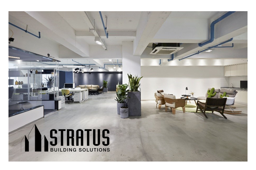 Open Modern Office with Concrete Floors, Cubicles on the Left, Sitting Area on the Right, and Potted Plants in the Middle 