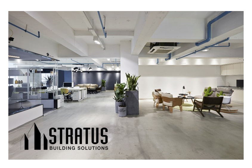 Open Modern Office with Concrete Floors, Cubicles on the Left, Sitting Area on the Right, and Potted Plants in the Middle 