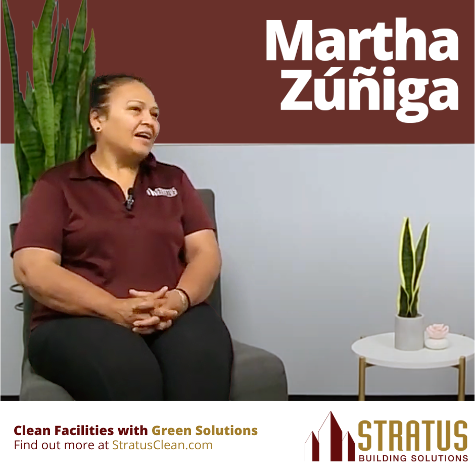 Martha Sitting on a Chair with a Small White Table in Front and a Green Plant in the Background