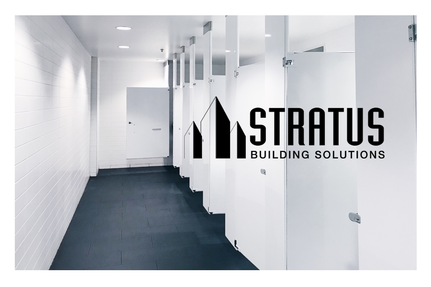 Clean office bathroom with clean white walls and stall doors and the Stratus logo in black