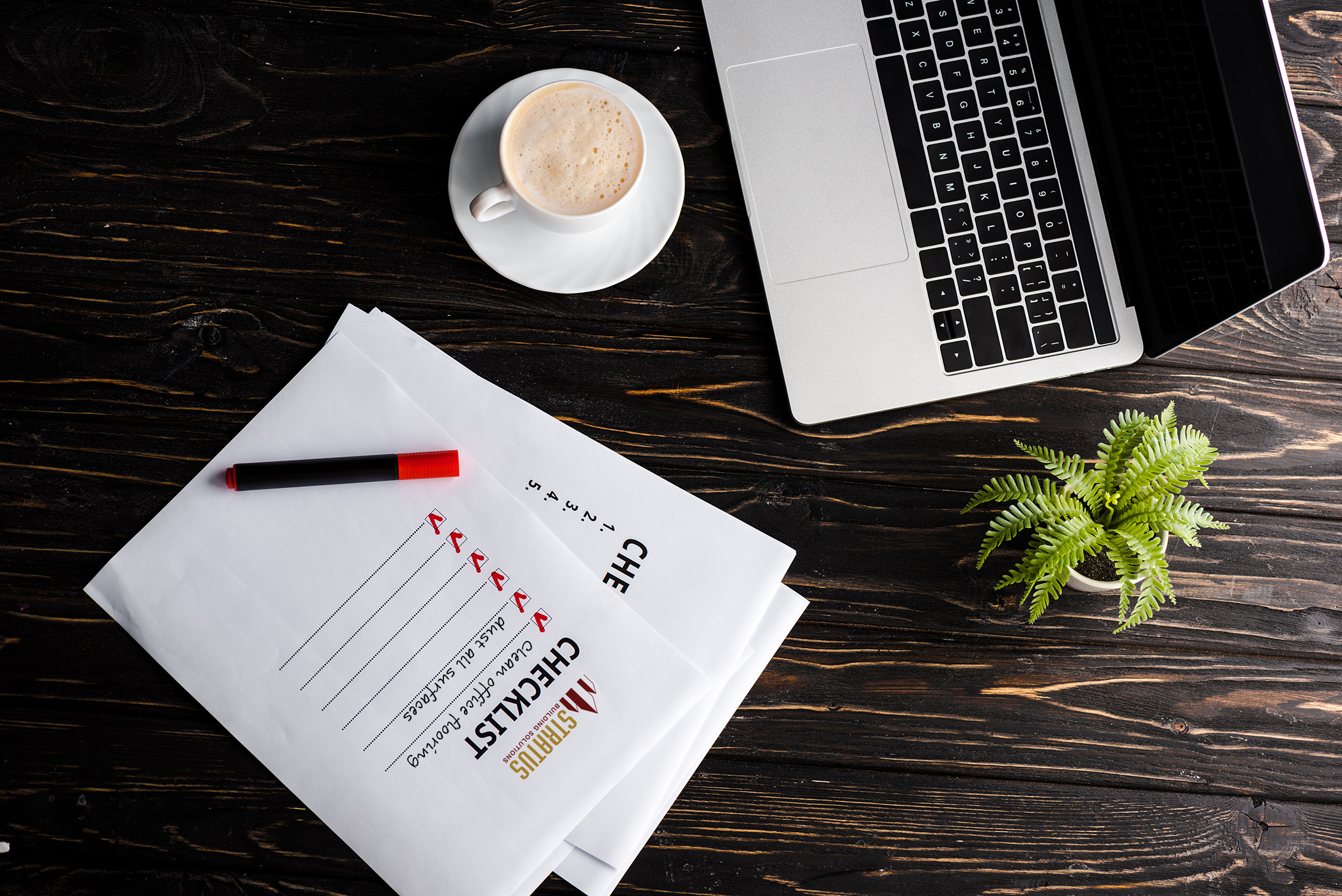 Papers with a checklist of item next to a laptop and cup of coffee