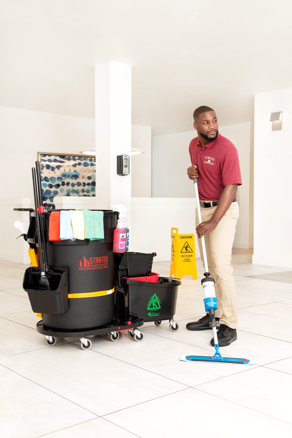 Stratus janitor holding a mop and cleaning the floor of a commercial building. 