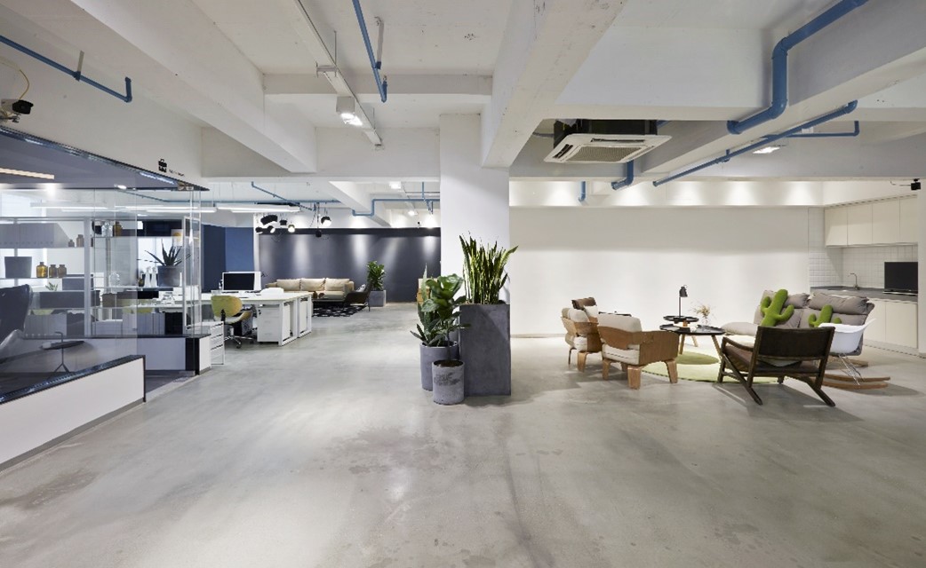 A picture of an office building with hard floors, plants, seating areas, and overhead lighting.