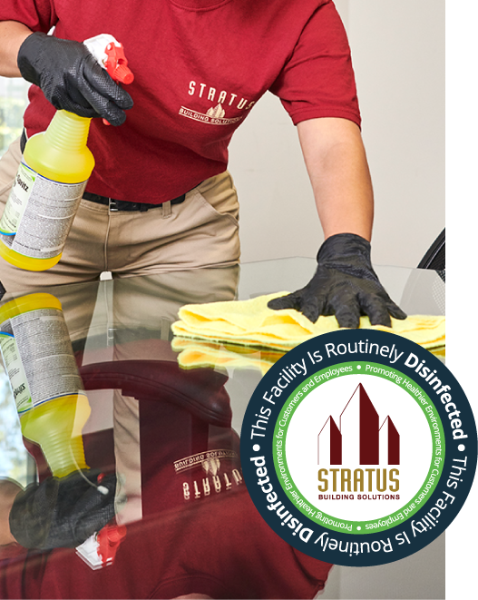 Stratus Building Solutions franchisee wiping down a conference table using a yellow microfiber cloth. 