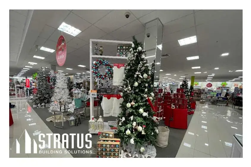 Interior of a retail store that is decorated for Christmas with several Christmas trees and ornaments. 