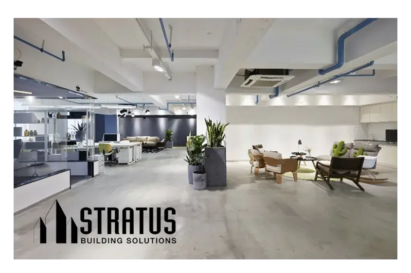 Open Modern Office with Concrete Floors, Cubicles on the Left, Sitting Area on the Right, and Potted Plants in the Middle 