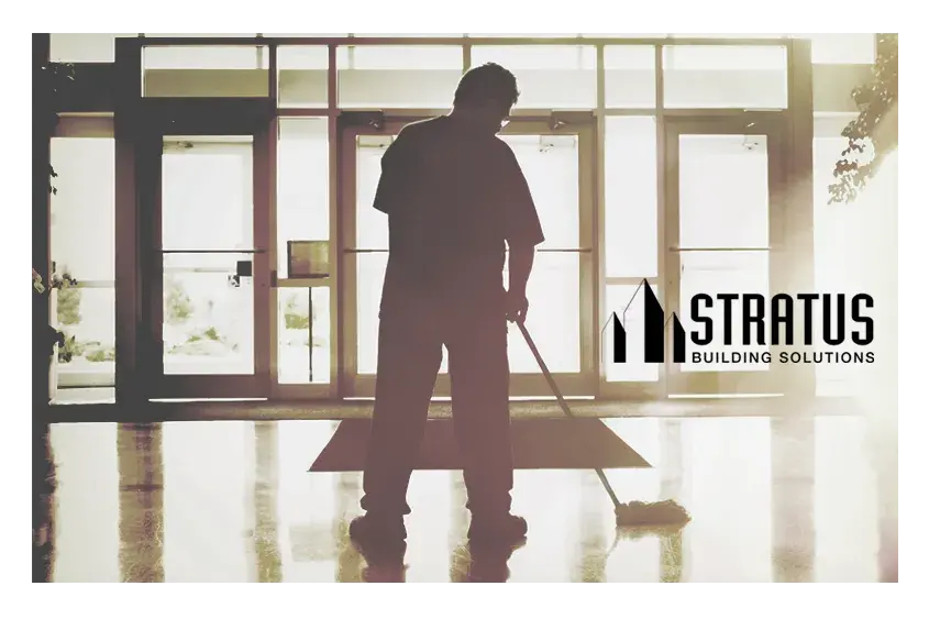 A janitor mopping the entryway of a building with the Stratus logo in black on the right side.